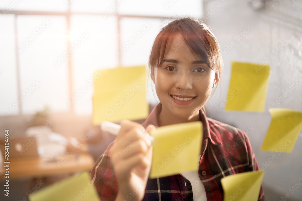 beautiful asian office worker woman using a marker pen writing ideas information or data on yellow sticky notes, working for business, company, or self-business owner, smiling wearing casual clothing beautiful asian office worker woman using a marker pen writing ideas information or data on yellow sticky notes, working for business, company, or self-business owner, smiling wearing casual clothing