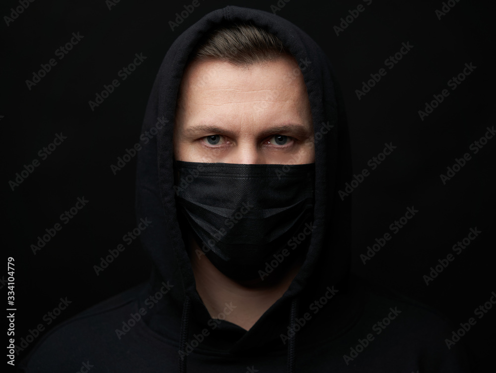 Young man wearing face mask over black background, close-up Young man wearing face mask over black background, close-up