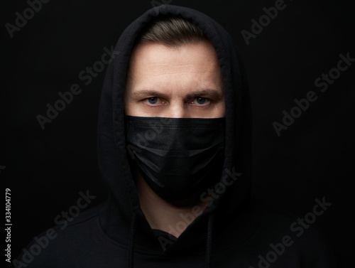 Young man wearing face mask over black background, close-up