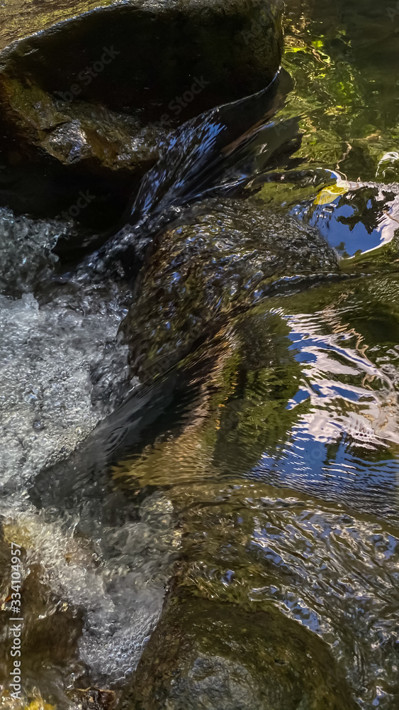 Water flows through rocks. Vertical background Water flows through rocks. Vertical background