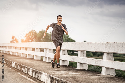 Billede på lærred asian teenager running along the bridge in sprinting action, exercising or pract