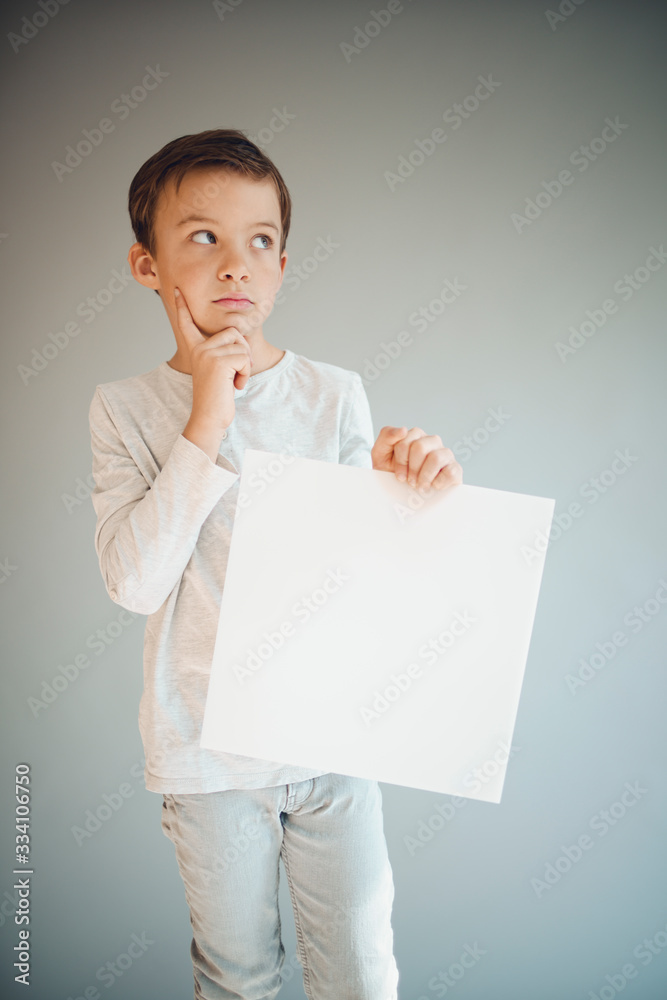 cool young boy is holding white sign in front of grey background during corona crisis cool young boy is holding white sign in front of grey background during corona crisis