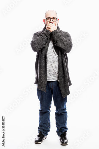 A bald man in jeans covered his mouth with his hands. Full height. White background. Vertical.