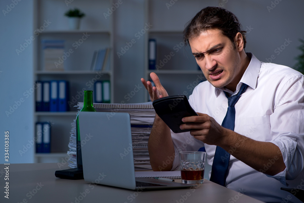Alcohol addicted businessman working late in the office Alcohol addicted businessman working late in the office