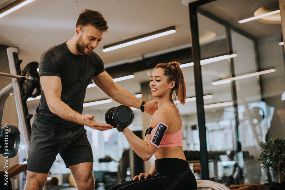 Attractive woman and a personal trainer with weight training at gym Attractive woman and a personal trainer with weight training at gym