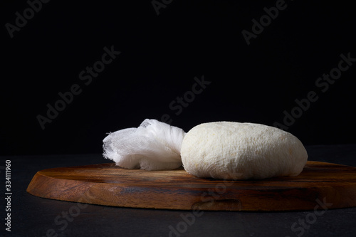 Traditional indian cheese paneer. Cooking vegetarian soft cheese in cheesecloth at home. Dark background, copy space