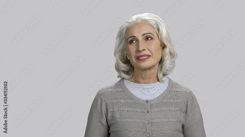 Old lady daydreaming about something pleasant. Recalling good memories. Grey isolated background. Old lady daydreaming about something pleasant. Recalling good memories. Grey isolated background.