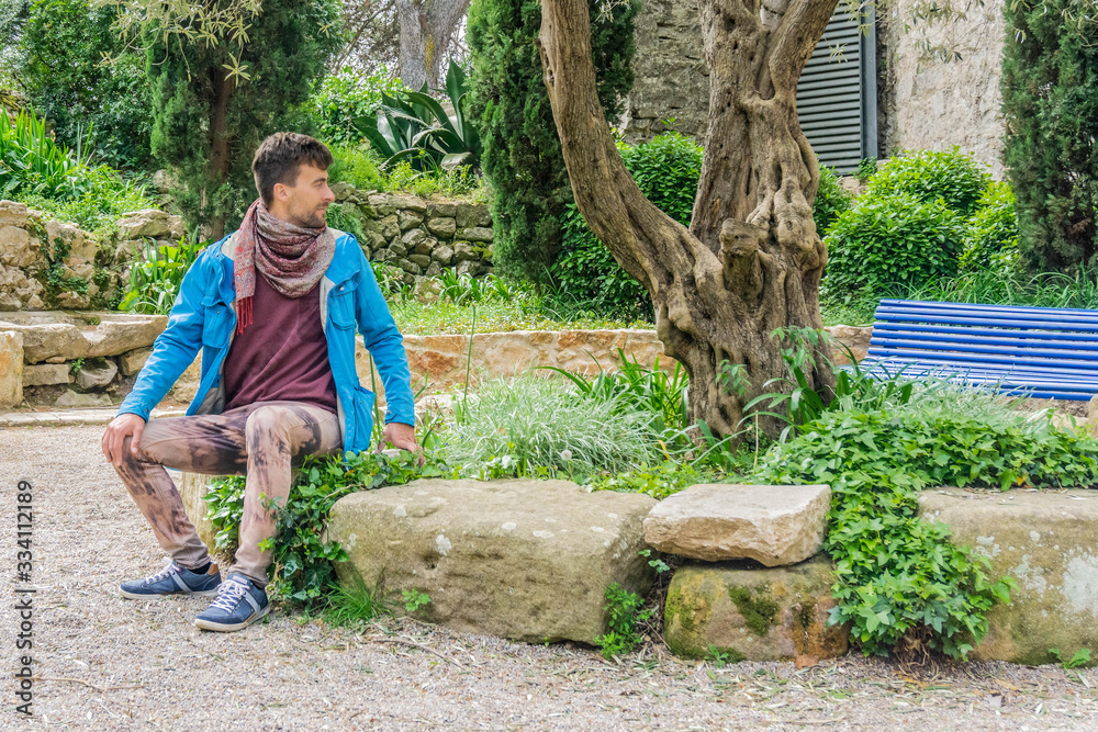 Attractive adult man sitting alone on bench in park Attractive adult man sitting alone on bench in park