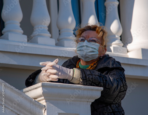 Wallpaper Mural An elderly woman in rubber gloves and a protective mask stands against a backdrop of white stone balustrades. Torontodigital.ca