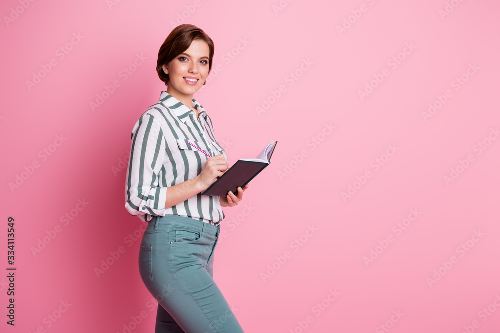 Portrait of positive cheerful girl hold paper note book pencil ready write report wear modern outfit isolated over pink color background Portrait of positive cheerful girl hold paper note book pencil ready write report wear modern outfit isolated over pink color background