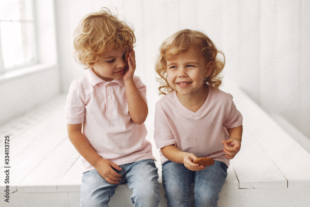 Children in a studio. Little girl with her brother. Boy in a pink t-shirt. Kids eating a cookies. Children in a studio. Little girl with her brother. Boy in a pink t-shirt. Kids eating a cookies.