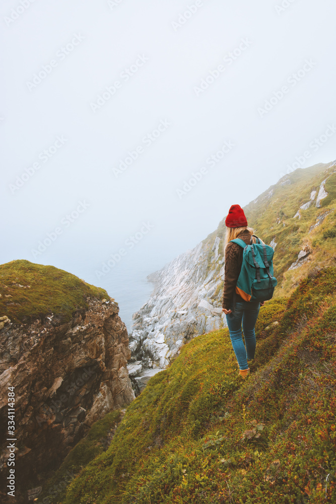Woman traveler with backpack standing alone outdoor summer vacations travel adventure lifestyle isolation solo trip concept foggy sea landscape in Norway