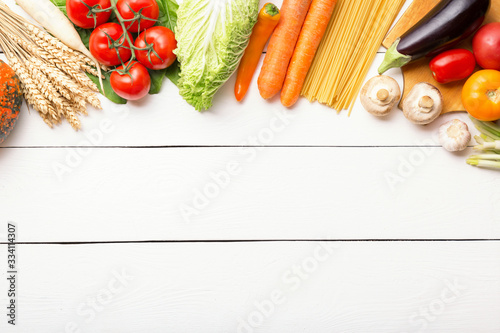 Assorted raw organic fresh vegetables on white wooden table. Fresh garden vegetarian food. Autumn seasonal image of farmer table with rye, pumpkin, cucumbers, tomatoes, eggplant, melon and onion.
