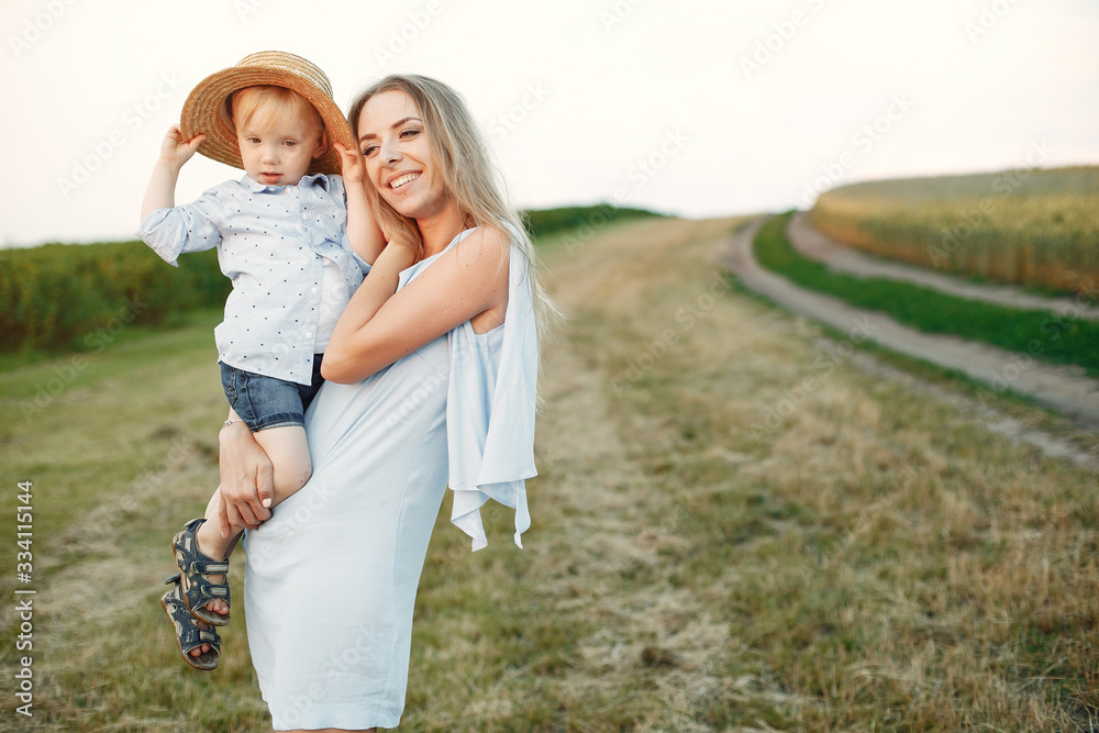 Family in a summer park. Mother in a blue dress. Cute little boy