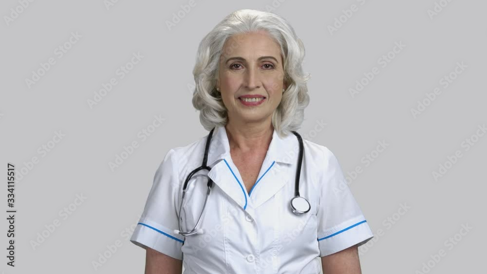 Portrait of old senior female doctor wearing stethoscope. Grey isolated background. Portrait of old senior female doctor wearing stethoscope. Grey isolated background.