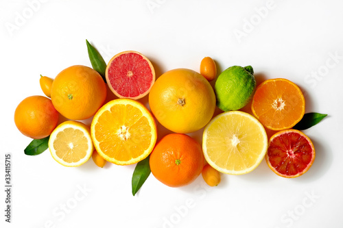 Close up image of juicy organic whole and halved assorted citrus fruits, green leaves & visible core texture, isolated white background, copy space. Vitamin C loaded food concept. Top view, flat lay.
