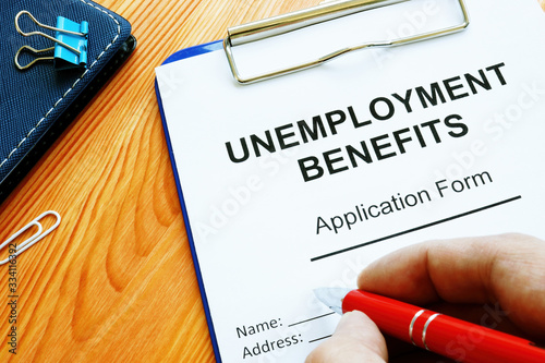 Man fills in Unemployment benefits application form. photo