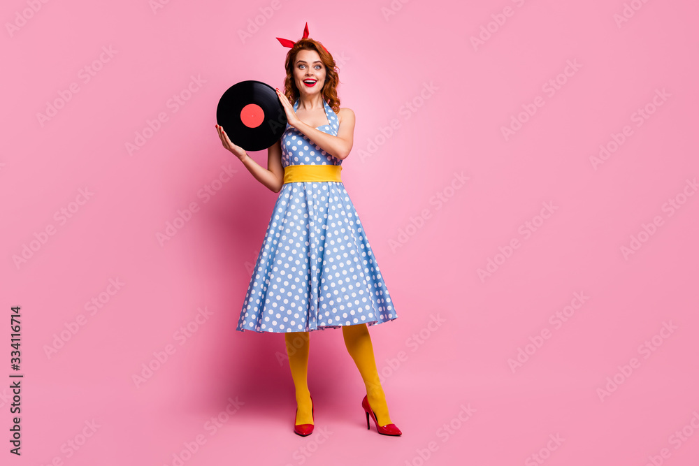 Full size photo of pretty amazed lady hold old fashion vinyl cd visit vintage retro theme party wear dotted long dress high-heels yellow tights isolated pink color background