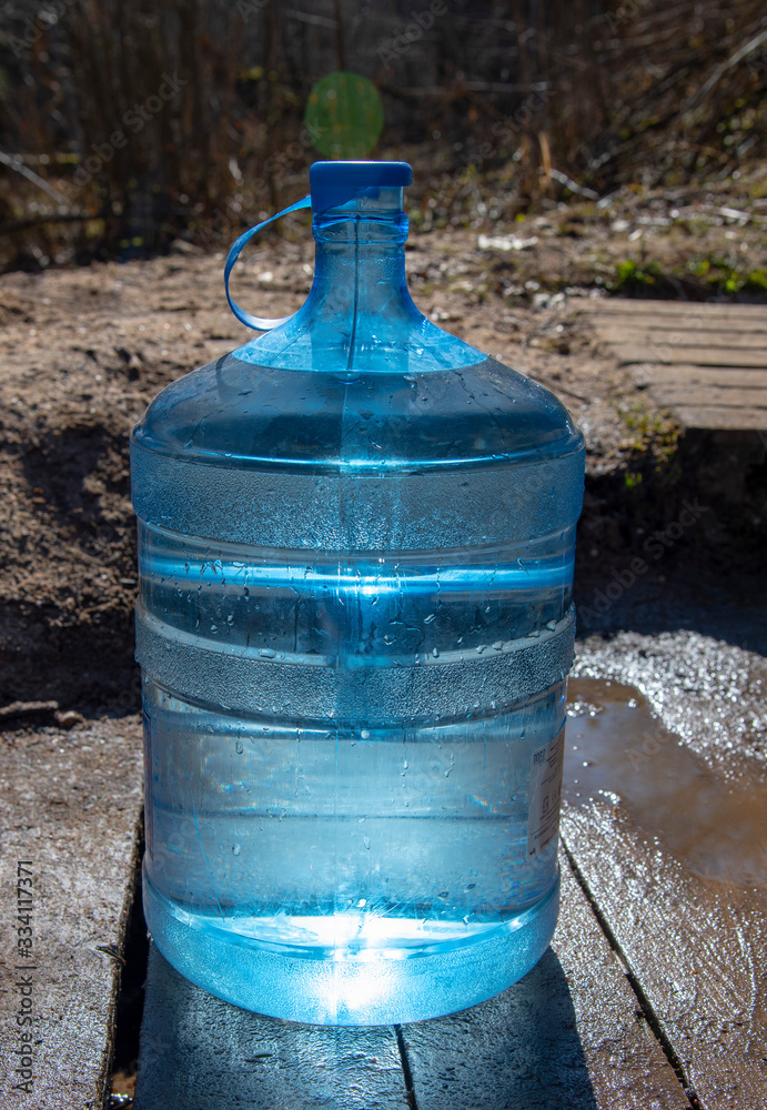 A nineteen-liter water bottle on a wooden walkway A nineteen-liter water bottle on a wooden walkway