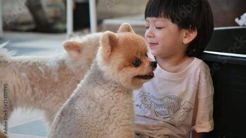 happy cute boy playing with pomeranian dog