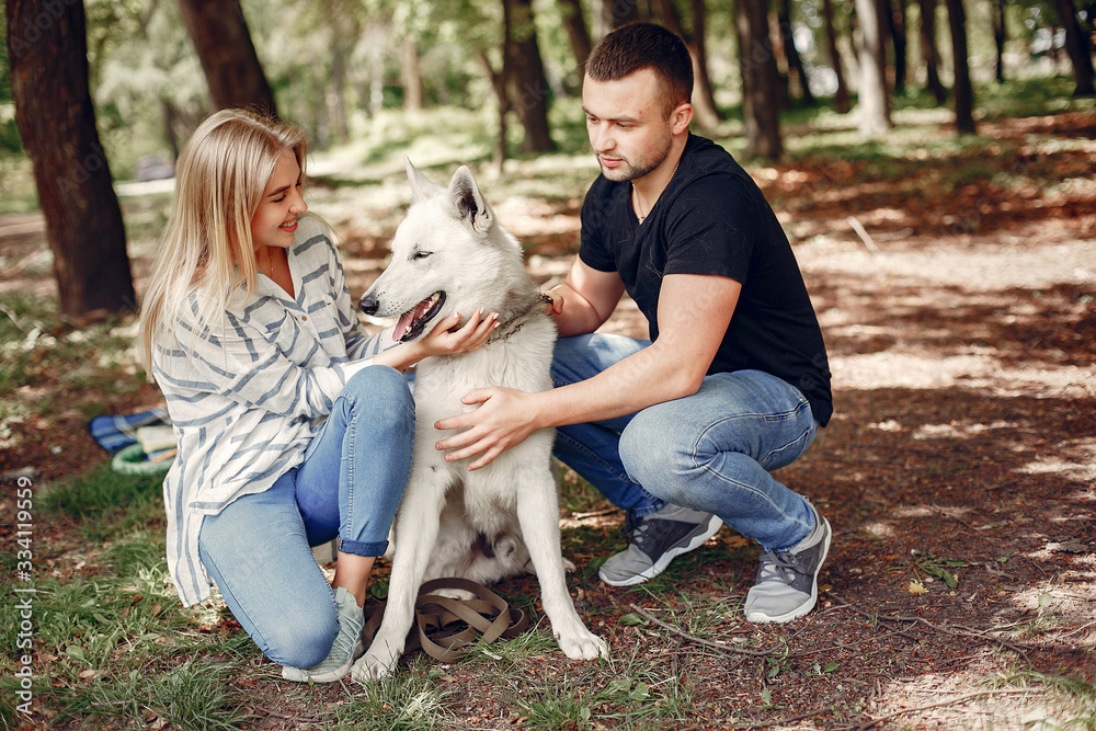Couple in a forest. Pair playing with a cute dog Couple in a forest. Pair playing with a cute dog