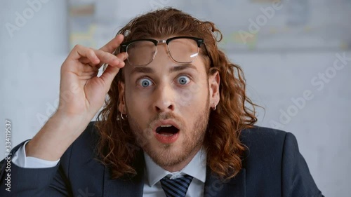 shocked and curly businessman looking at camera photo
