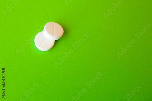 white pills on a green background. snow-white round antibiotics against viruses photo