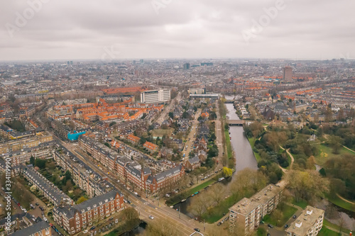 Aerial Amsterdam view from above in cloudy day, canals, streets and architectures.