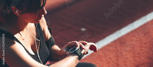 Plump caucasian woman listening to music while looking at her watches and making sport