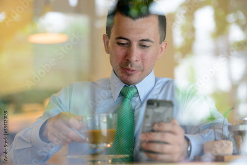 Young businessman with phone drinking coffee at the coffee shop