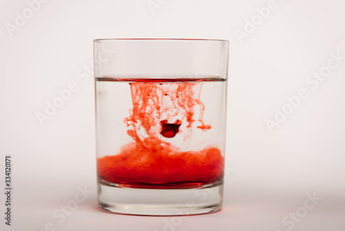 Drops of blood in glass with water on white surface