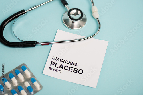 Card with placebo effect lettering, pills and stethoscope on blue background photo