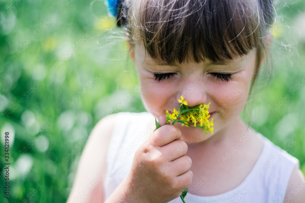 A little girl in dress sniffing flowers in the garden.Portrait of smiling cute little girl outdoors.little girl sniffs flowers with her eyes closed. A little girl in dress sniffing flowers in the garden.Portrait of smiling cute little girl outdoors.little girl sniffs flowers with her eyes closed.