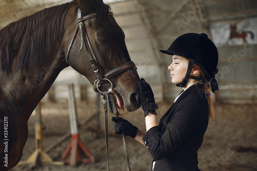 Woman near horse. Rider in a black uniform © prostooleh