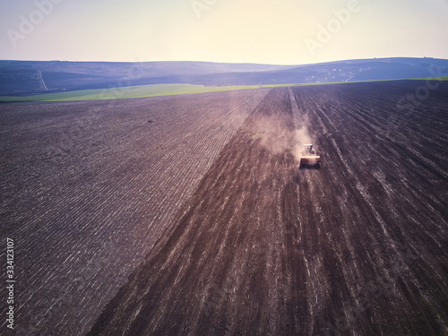 Tractor in a field performing spring sowing., top view from drone pov photo