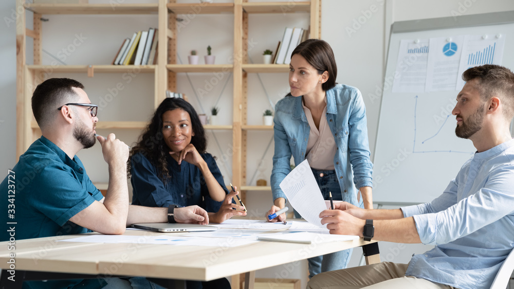 Focused diverse colleagues gather at desk in office discuss business ideas paperwork together, concentrated multiracial businesspeople brainstorm talk consider project at meeting, teamwork concept Focused diverse colleagues gather at desk in office discuss business ideas paperwork together, concentrated multiracial businesspeople brainstorm talk consider project at meeting, teamwork concept