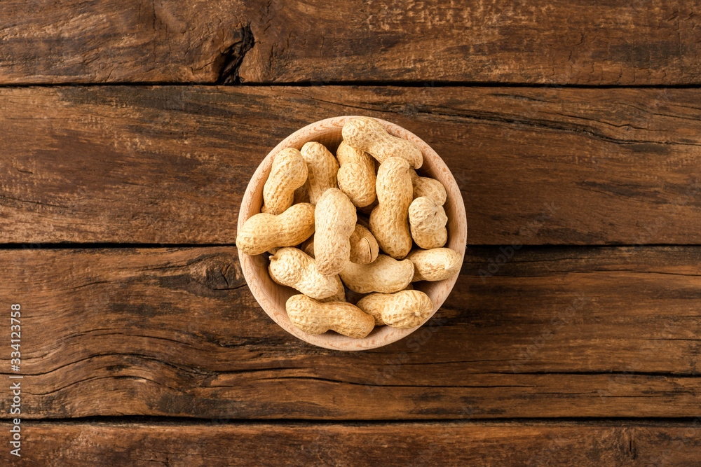 Overhead shot of peanuts in bowl on wooden table. Healthy snacks Overhead shot of peanuts in bowl on wooden table. Healthy snacks