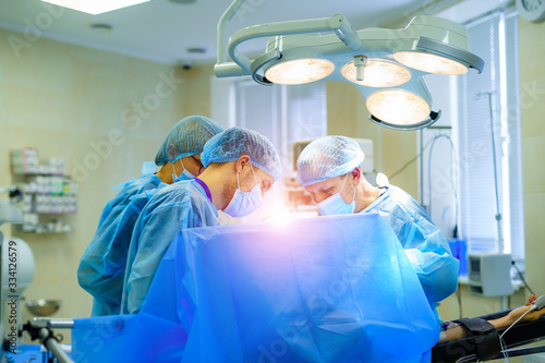 Process of trauma surgery operation. Group of surgeons in operating room with surgery equipment. Medical background, selective focus