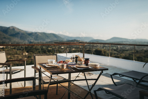 table and chairs with breakfast on terrace in front of mountains © Danny