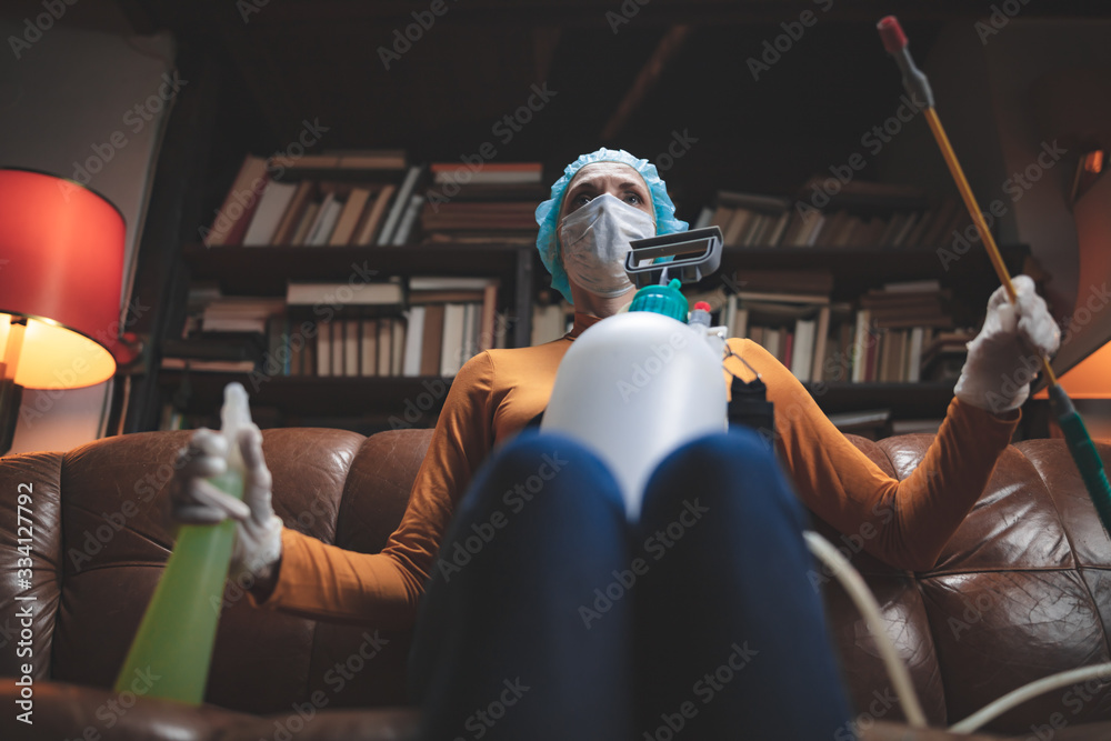 Obraz premium Woman with protective antiviral mask, chemical decontamination sprayer bottle in home isolation.