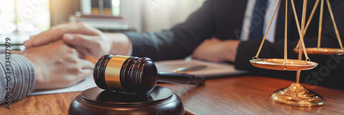 Lawyer working with client discussing contract papers with brass scale about legal legislation in courtroom, consulting to help their customer.