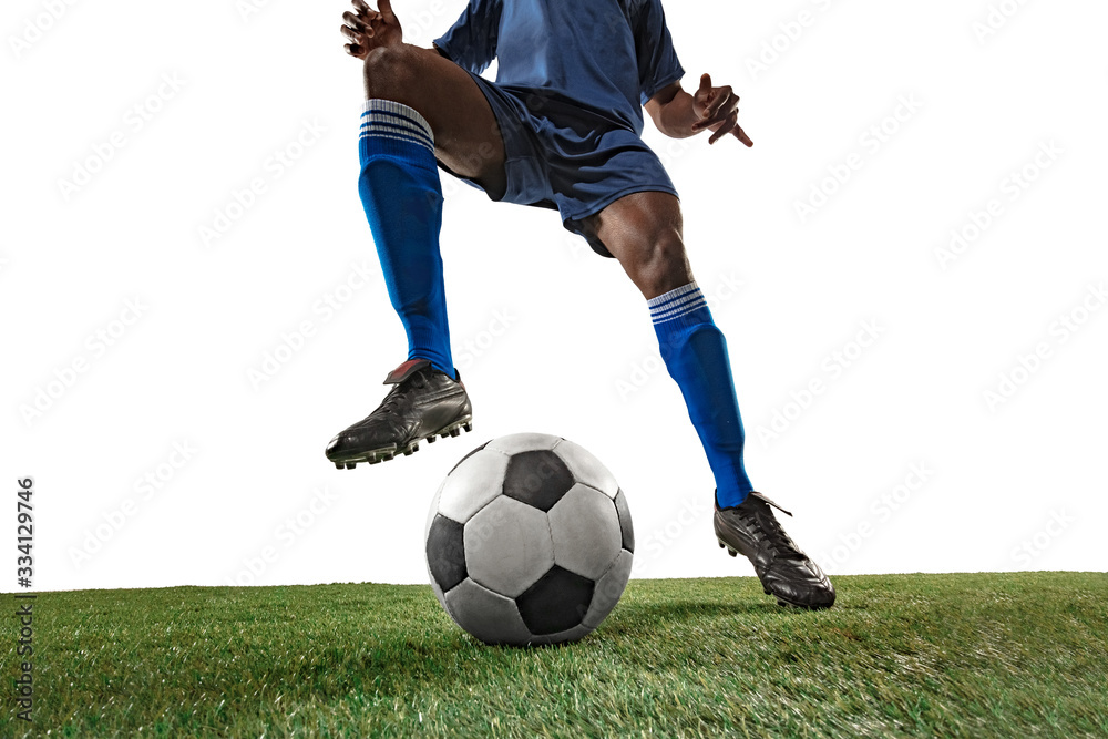 Football or soccer player on white background with grass. Young male sportive model training, practicing. Attacking, catching. Concept of sport, competition, winning, motion, overcoming. Wide angle.