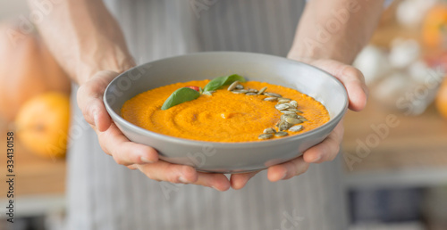 Man holding fresh hot pumpkin carrot soup