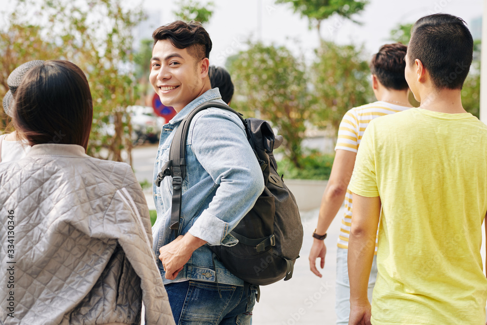 Handsome young Vietnamese student in denim jacket carrying backpack when going to college Handsome young Vietnamese student in denim jacket carrying backpack when going to college