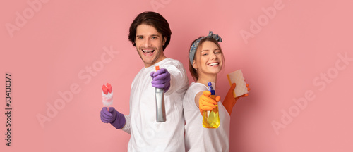 Cheerful Couple With Sprayers And Cleaning Tools Posing On Pink Background