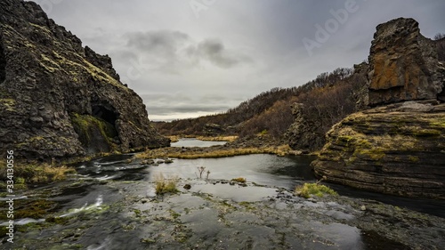 Dark lake, marsh next to a stony cliff covered in moss. Iceland nature landscape.