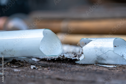 Shattered glass tube, broken energy saving bulb, compact fluorescent lamp tubular type with blur background