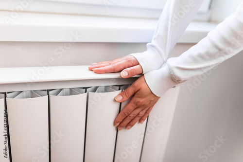 Heavy duty radiator - central heating. Woman is getting her hands warm on Home central heating system