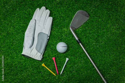 A golf glove ,colorful ball ,tee and gold club put on green grass of golf course ,This objects for play