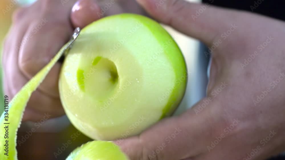 mains qui épluche une pomme en cuisine